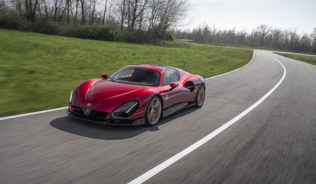 Alfa Romeo 33 Stradale rojo circula en una carretera de curvas, símbolo de la deportividad y diseño italiano de la marca.