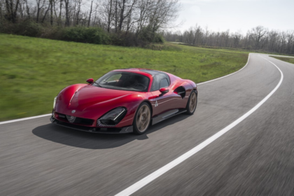 Alfa Romeo 33 Stradale rojo circula en una carretera de curvas, símbolo de la deportividad y diseño italiano de la marca.