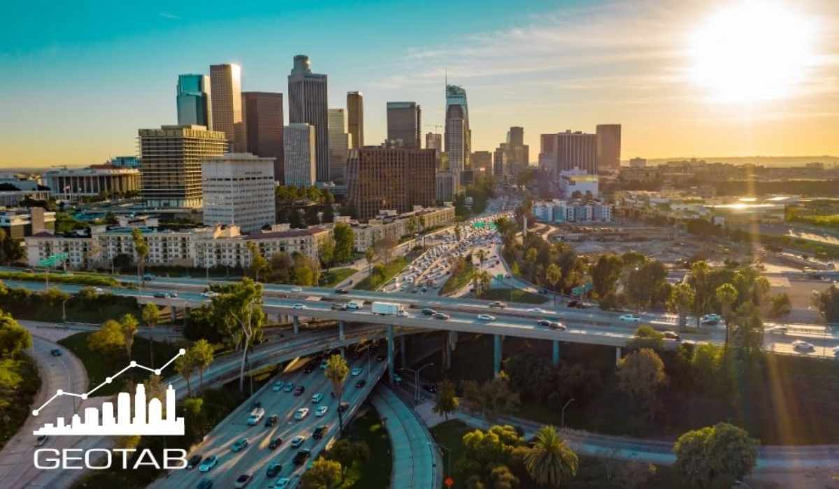 Vista aérea de una zona urbana con autopistas, tráfico vehicular y edificios de gran altura utilizada por Geotab para ilustrar un estudio de movilidad vial.