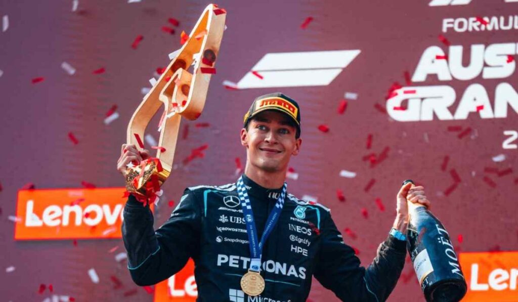 George Russell sostiene el trofeo y una botella de champaña durante la ceremonia del podio tras ganar el Gran Premio de Austria con Mercedes.