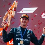 George Russell sostiene el trofeo y una botella de champaña durante la ceremonia del podio tras ganar el Gran Premio de Austria con Mercedes.