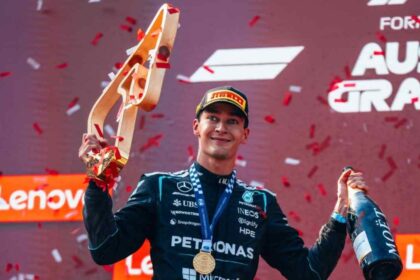 George Russell sostiene el trofeo y una botella de champaña durante la ceremonia del podio tras ganar el Gran Premio de Austria con Mercedes.