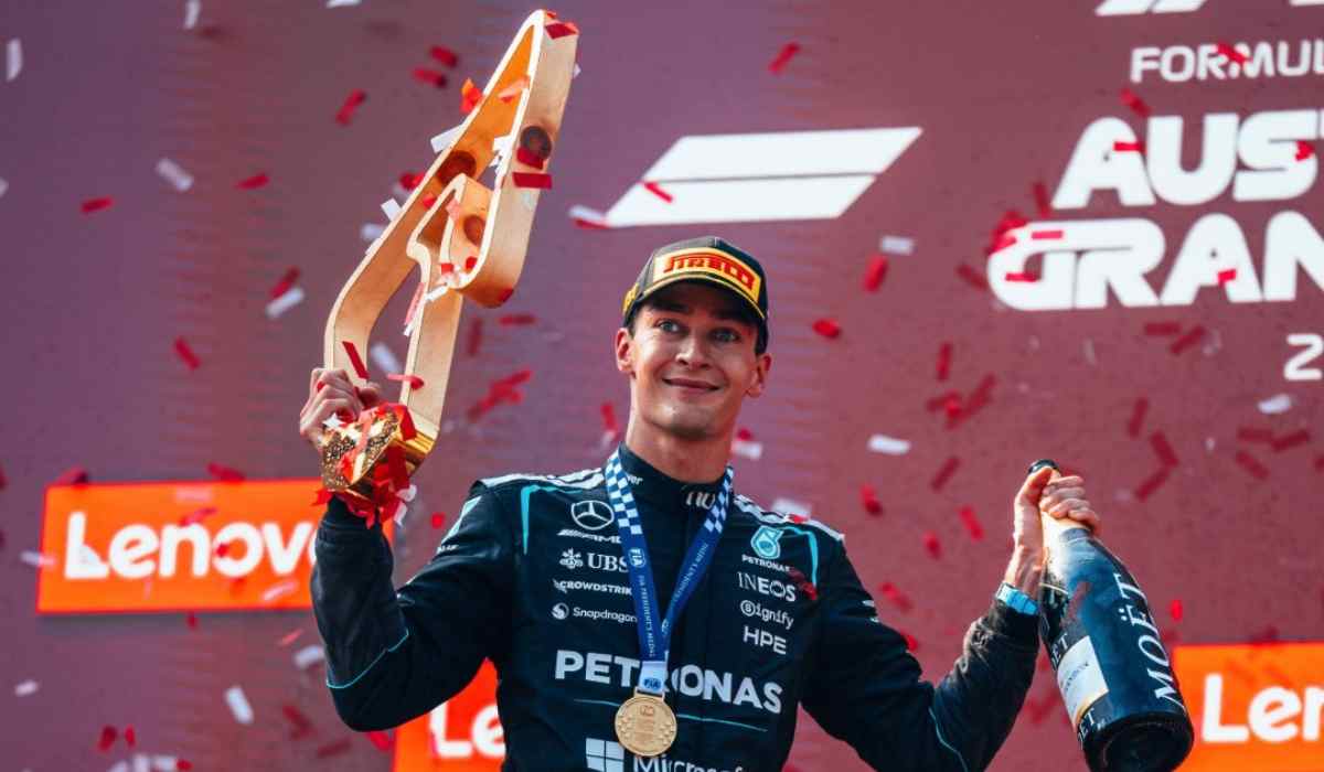 George Russell sostiene el trofeo y una botella de champaña durante la ceremonia del podio tras ganar el Gran Premio de Austria con Mercedes.