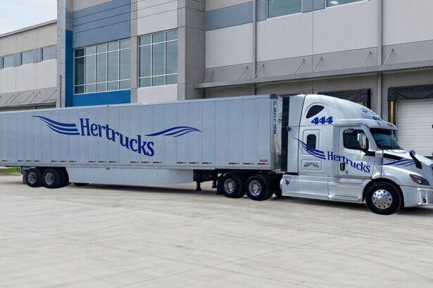 Tractocamión de Hertrucks con caja seca estacionado frente a un centro de distribución y logística.