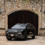 JAC 6 PHEV color negro estacionado frente a una fachada de piedra con puertas de madera de estilo colonial