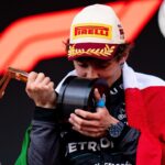 Kimi Antonelli besa un trofeo durante la ceremonia de podio mientras porta la bandera de México.