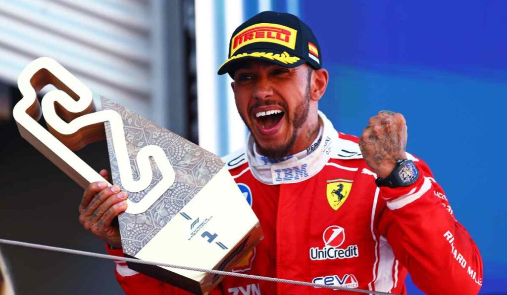 Lewis Hamilton celebra en el podio tras ganar el Gran Premio de Barcelona con Ferrari mientras sostiene el trofeo de ganador.