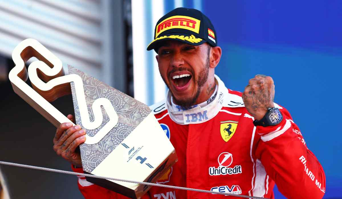 Lewis Hamilton celebra en el podio tras ganar el Gran Premio de Barcelona con Ferrari mientras sostiene el trofeo de ganador.