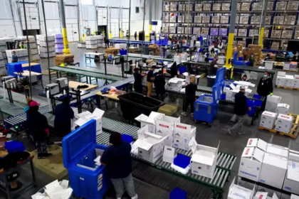 Personal opera un centro logístico con sistemas de clasificación y embalaje para productos sensibles a la temperatura dentro de una instalación de distribución.