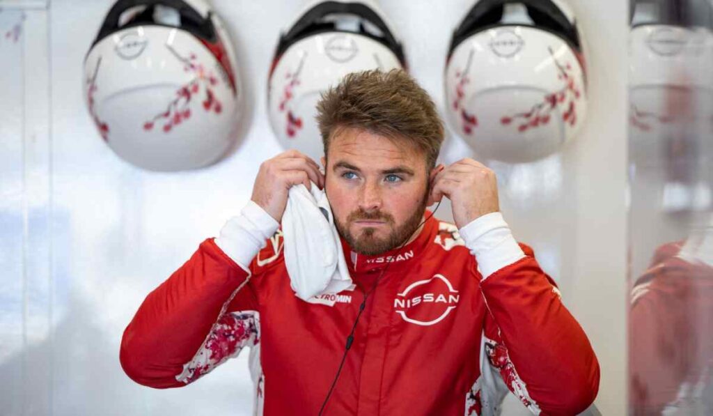 Piloto de Nissan Formula E en el garaje del equipo mientras ajusta sus auriculares antes de una sesión de competencia.