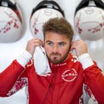 Piloto de Nissan Formula E en el garaje del equipo mientras ajusta sus auriculares antes de una sesión de competencia.