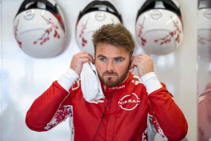 Piloto de Nissan Formula E en el garaje del equipo mientras ajusta sus auriculares antes de una sesión de competencia.