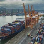 Buque portacontenedores atracado en una terminal del Puerto de Manzanillo junto a grúas pórtico y patios de almacenamiento de contenedores.