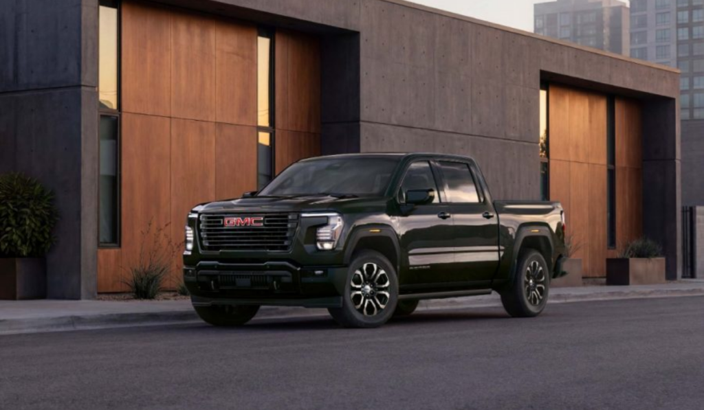 GMC Sierra 1500 2027 color verde oscuro estacionada frente a un edificio moderno, mostrando el nuevo diseño exterior de la pickup.