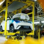 Automóvil blanco en proceso de ensamblaje sobre una línea de producción automatizada en una fábrica automotriz.