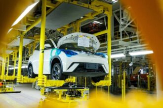 Automóvil blanco en proceso de ensamblaje sobre una línea de producción automatizada en una fábrica automotriz.