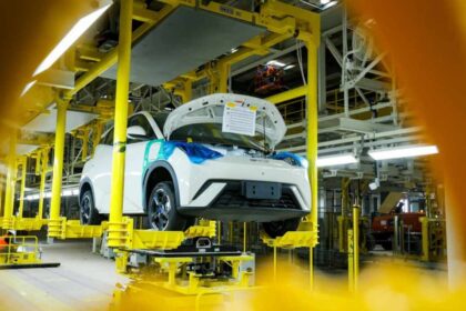 Automóvil blanco en proceso de ensamblaje sobre una línea de producción automatizada en una fábrica automotriz.