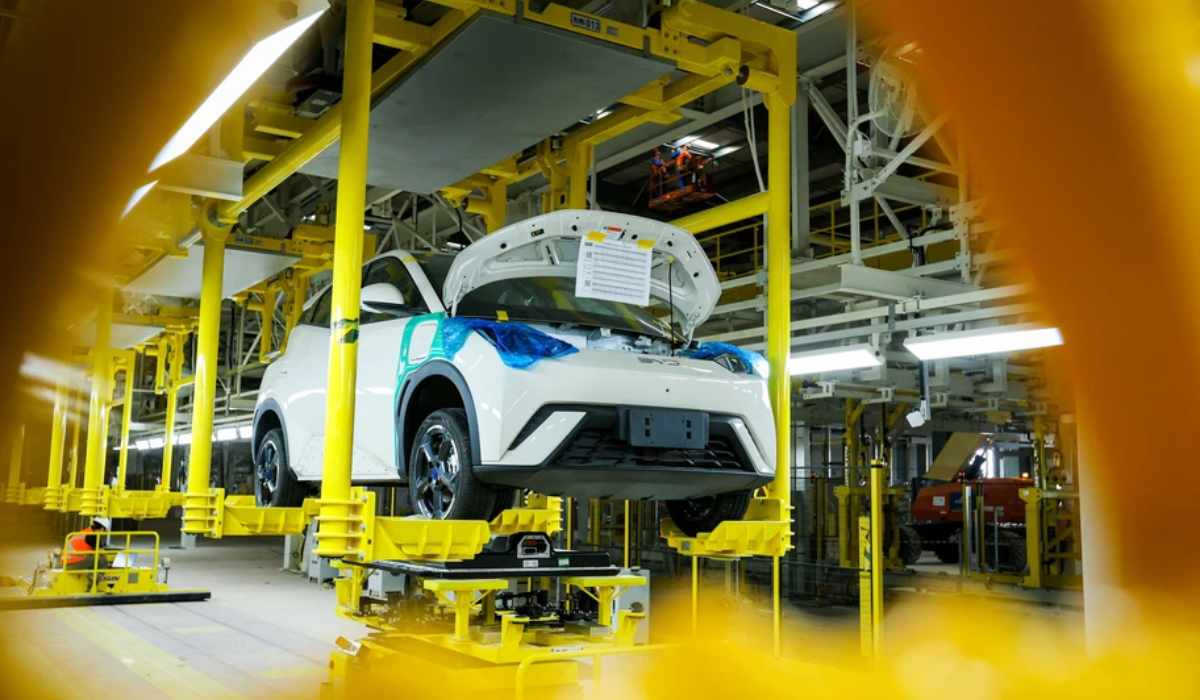 Automóvil blanco en proceso de ensamblaje sobre una línea de producción automatizada en una fábrica automotriz.
