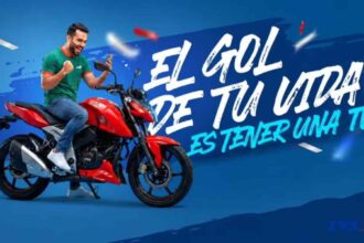 Persona celebrando sobre una motocicleta TVS roja durante la campaña promocional El gol de tu vida es tener una TVS