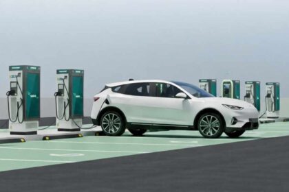 Vehículo eléctrico blanco conectado a una estación de carga rápida en un hub de recarga de VEMO con múltiples cargadores disponibles.