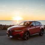 Alfa Romeo Junior rojo frente al mar durante un atardecer de verano