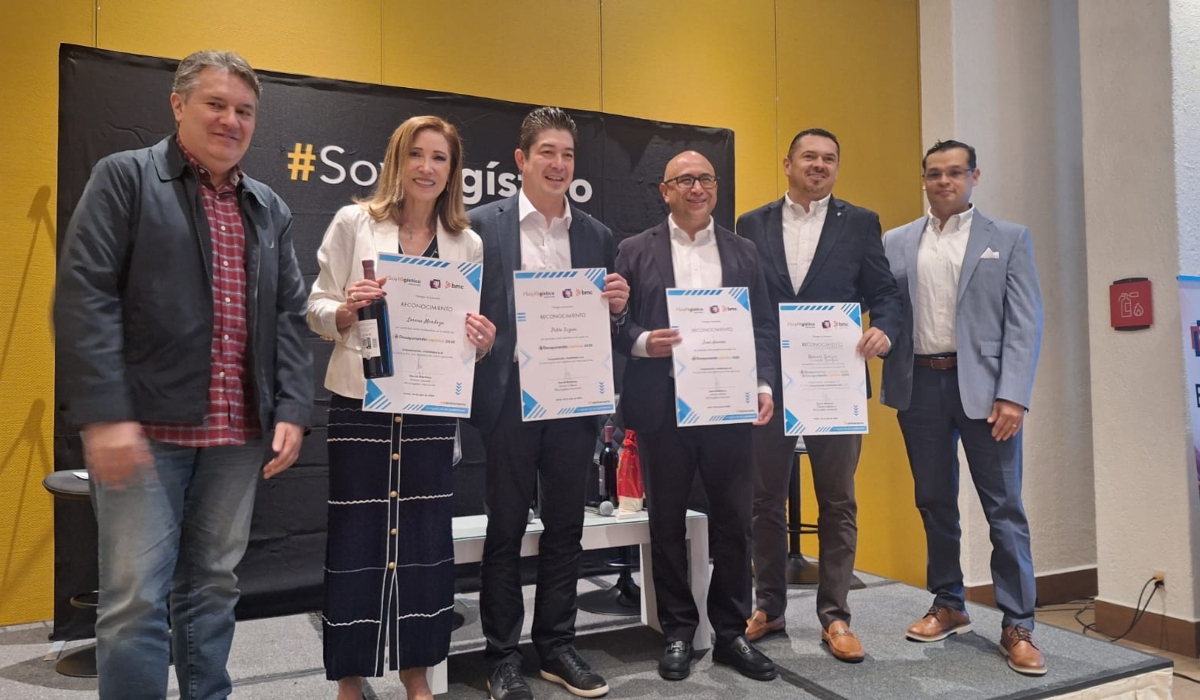 Grupo de directivos posando con reconocimientos de SoyLogístico durante evento corporativo sobre un escenario.