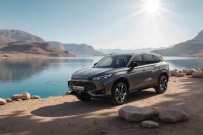 SUV MG gris junto a un lago rodeado de montañas
