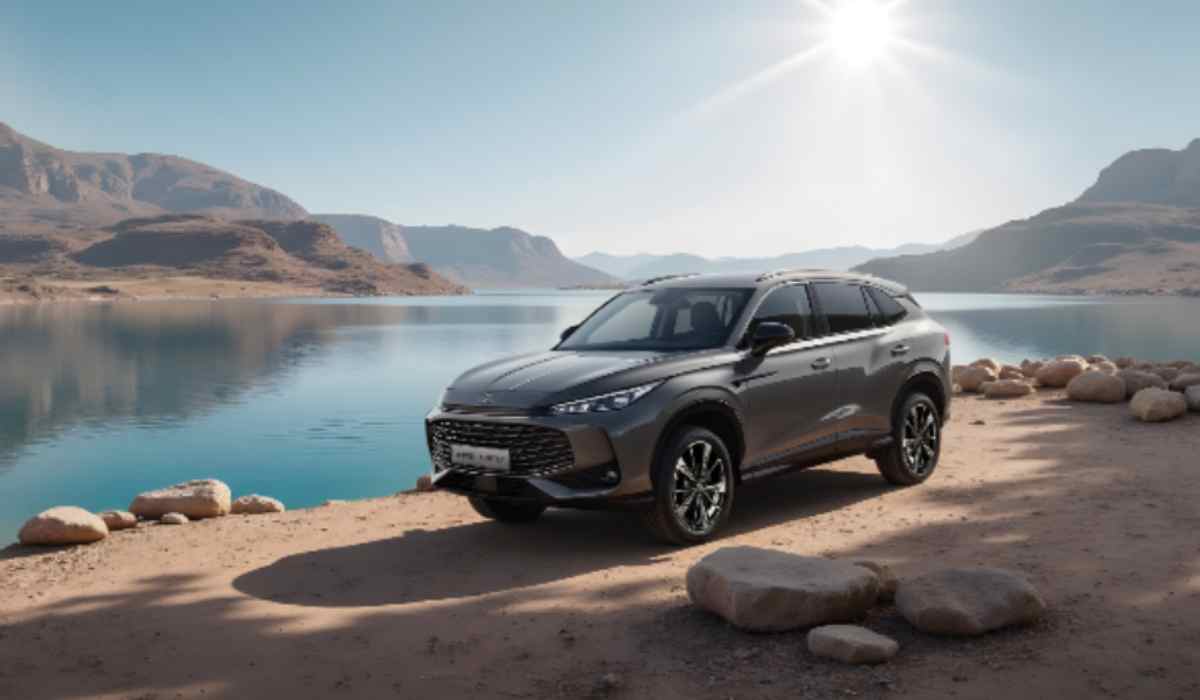 SUV MG gris junto a un lago rodeado de montañas