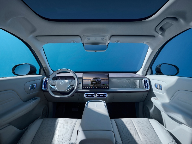 Interior del Leapmotor B10 con volante multifunción, pantalla táctil de 14.6 pulgadas y techo panorámico visto desde los asientos traseros.