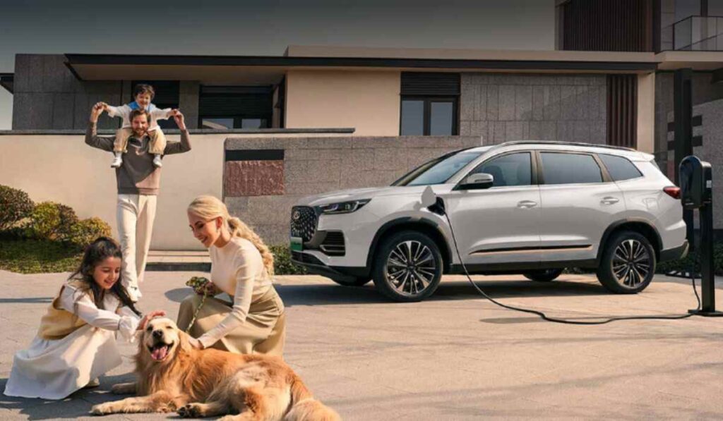 Una familia de cuatro integrantes con un perro Golden Retriever conviviendo frente a una SUV Chirey Tiggo PHEV de color blanco conectada a una estación de carga en casa.