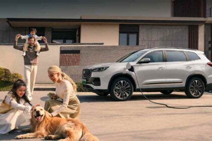 Una familia de cuatro integrantes con un perro Golden Retriever conviviendo frente a una SUV Chirey Tiggo PHEV de color blanco conectada a una estación de carga en casa.
