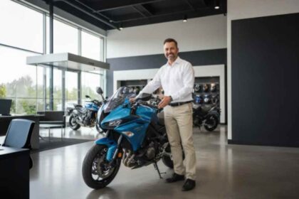 Hombre posando sonriente junto a una moto deportiva azul en una agencia de ventas, ilustrando los consejos para elegir la primera motocicleta.