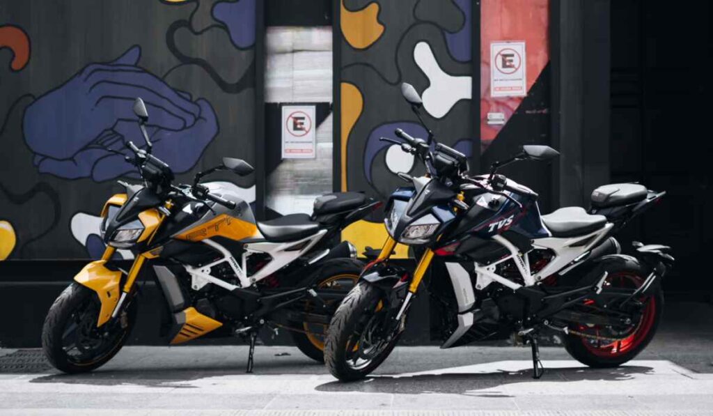 Dos motocicletas deportivas TVS Apache RTR 310 en colores amarillo y azul estacionadas frente a un mural urbano.
