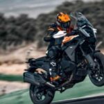 Motociclista con equipo de protección realizando un wheelie en una motocicleta KTM touring en pista, representando el arquetipo de conductor viajero y competitivo.