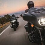Dos motocicletas Indian tipo bagger navegando en carretera al atardecer equipadas con sistemas de seguridad inteligente SmartLean y cascos de protección.