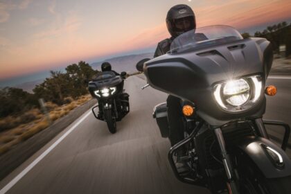 Dos motocicletas Indian tipo bagger navegando en carretera al atardecer equipadas con sistemas de seguridad inteligente SmartLean y cascos de protección.