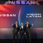 Tres ejecutivos de Nissan en el escenario apuntando hacia arriba frente a una pantalla con la inscripción Nissan Vision Latam.