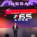 Presentador en escenario durante la celebración del 65 aniversario de Nissan Mexicana con la pantalla gigante iluminada de fondo.
