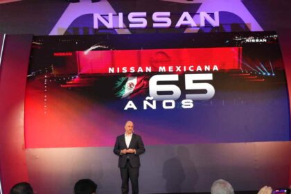 Presentador en escenario durante la celebración del 65 aniversario de Nissan Mexicana con la pantalla gigante iluminada de fondo.