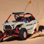 Polaris RZR Pro R Boost 2027 circulando a alta velocidad sobre dunas de arena en una prueba de desempeño off-road.