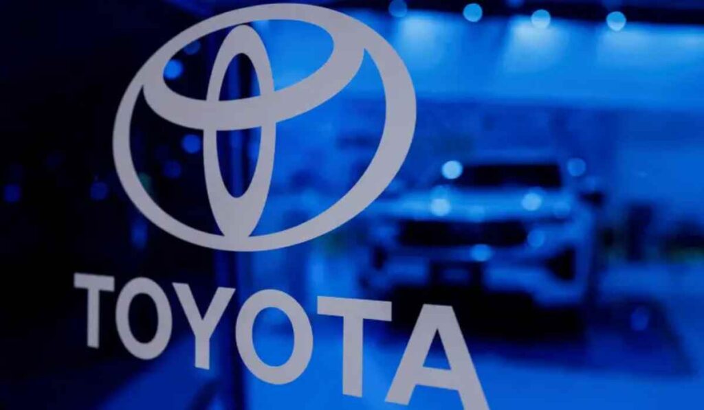 Logotipo corporativo de Toyota iluminado en azul con la silueta de un vehiculo desenfocada al fondo, representando la estrategia financiera y de movilidad de la marca.
