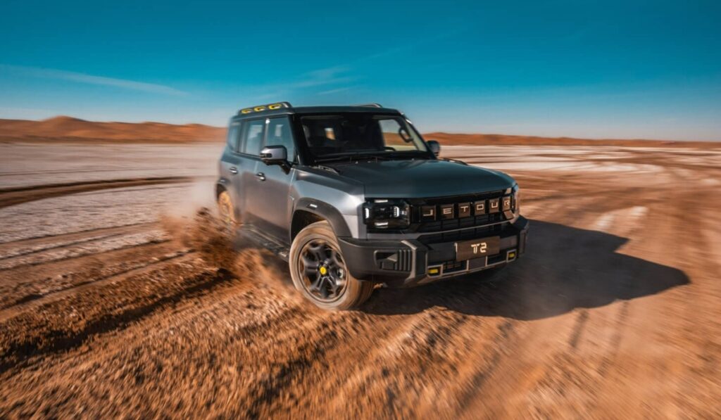SUV todoterreno JETOUR T2 gris en movimiento sobre terreno desértico destacando la estrategia de expansión global Travel+.