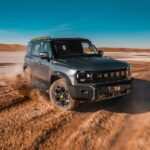 SUV todoterreno JETOUR T2 gris en movimiento sobre terreno desértico destacando la estrategia de expansión global Travel+.