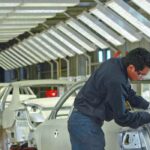 Trabajador realiza labores de ensamblaje en una línea de producción de vehículos ligeros