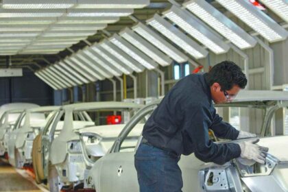 Trabajador realiza labores de ensamblaje en una línea de producción de vehículos ligeros