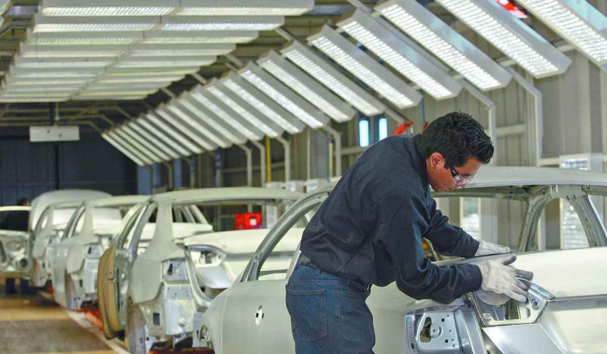Trabajador realiza labores de ensamblaje en una línea de producción de vehículos ligeros