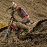 Piloto de Honda HRC Progressive maniobrando su motocicleta cubierta de lodo en una pista extrema del Campeonato SMX en Columbus, Ohio.