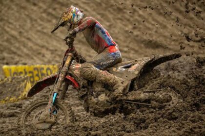 Piloto de Honda HRC Progressive maniobrando su motocicleta cubierta de lodo en una pista extrema del Campeonato SMX en Columbus, Ohio.