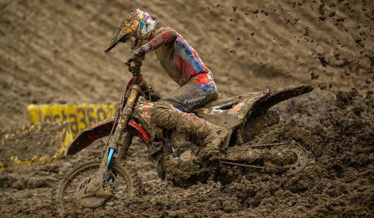 Piloto de Honda HRC Progressive maniobrando su motocicleta cubierta de lodo en una pista extrema del Campeonato SMX en Columbus, Ohio.
