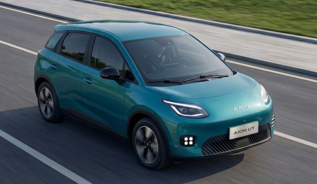 Vehículo eléctrico compacto GAC AION UT en color verde turquesa circulando sobre el asfalto.